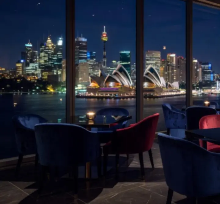Elegant dining room with panoramic views over Sydney's skyline at night.